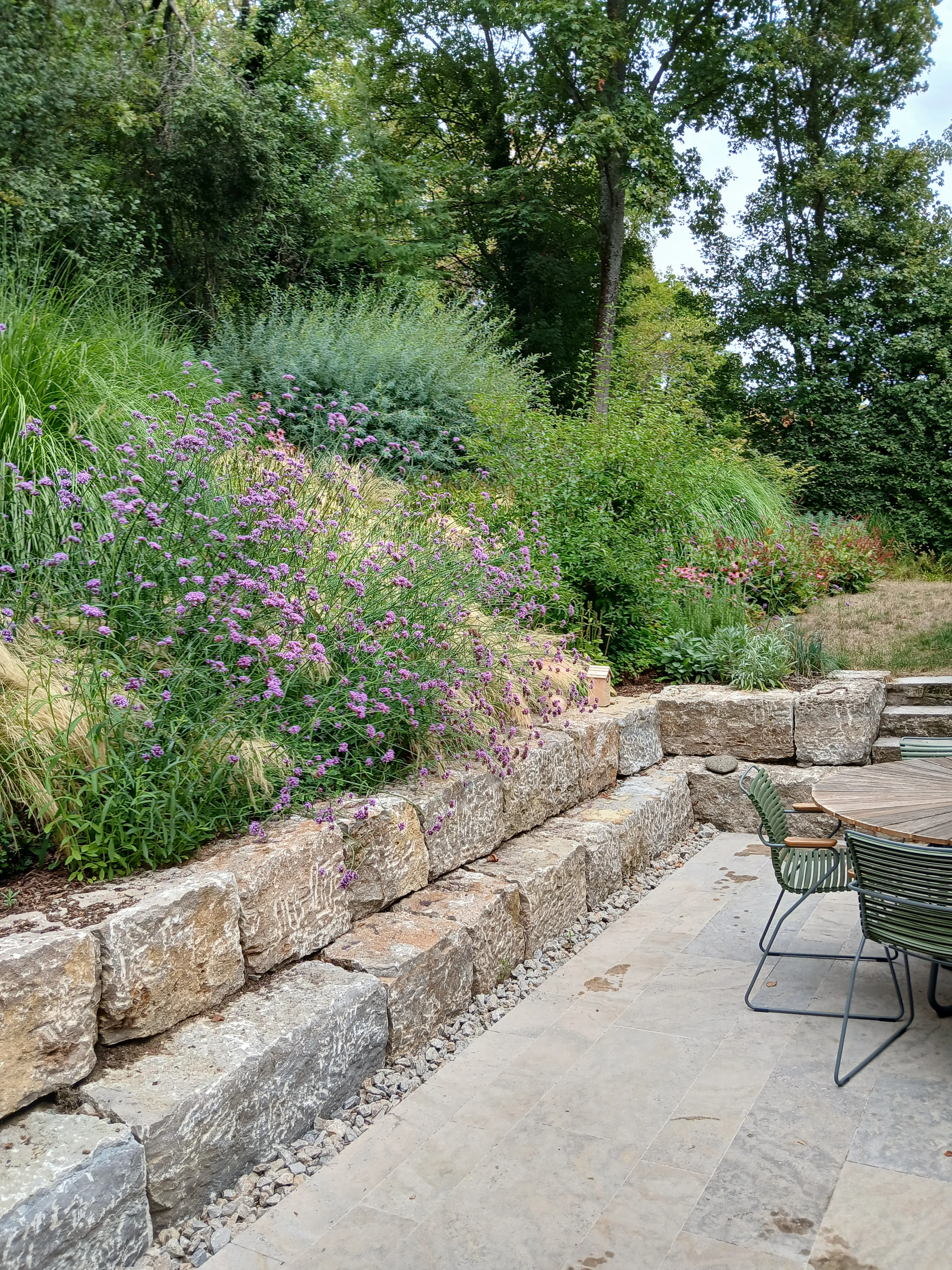 Natursteinmauer mit blühender Bepflanzung in einem Garten von Garten Lindner
